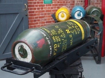 A large green and yellow bomb on a black platform  Description automatically generated